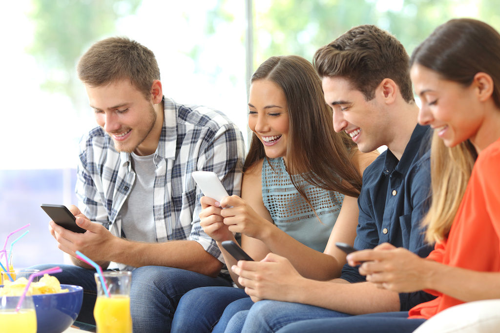 Two young men and two young women all looking at their cell phones